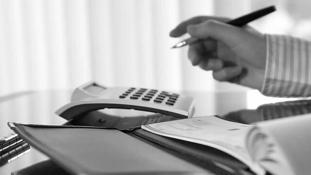 Businesswoman writing a cheque in the office with black and white toned