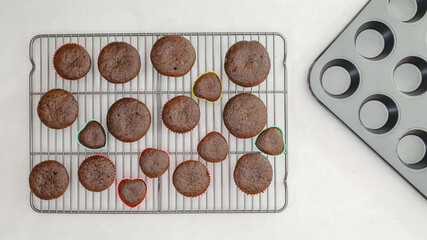 Chocolate cupcakes close up on cooling rack on light grey background directly from above