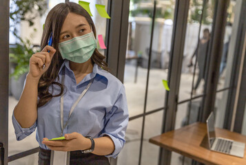 Business in new normal. Office female worker wearing face mask while having self brainstorming for new business strategy