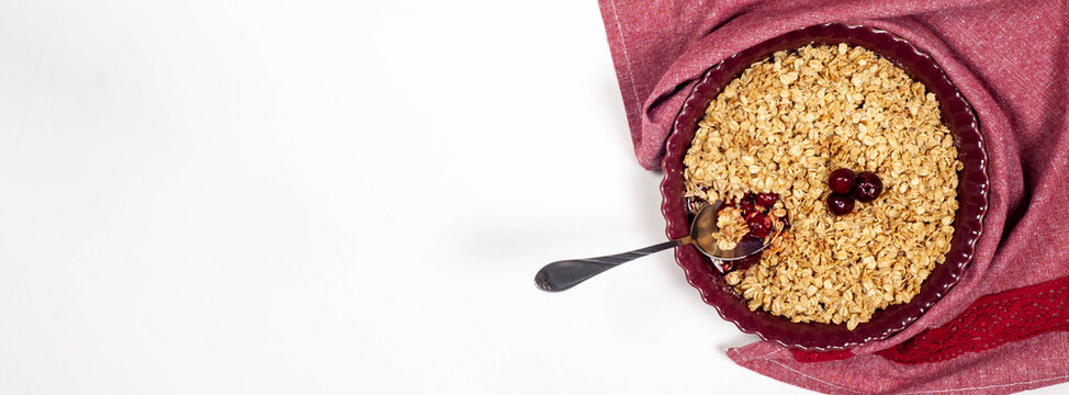 Oatmeal cherry crumble on a white background. Place for text. View from above. Banner.