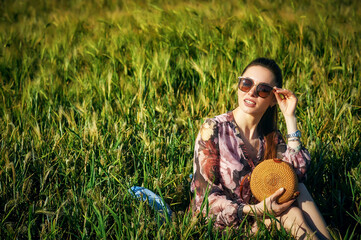 Portrait of a beautiful young girl in nature. Young woman in a summer dress and sun glasses