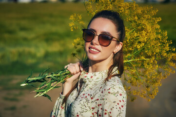 Portrait of a beautiful young girl in nature. Young woman in a summer dress and sun glasses