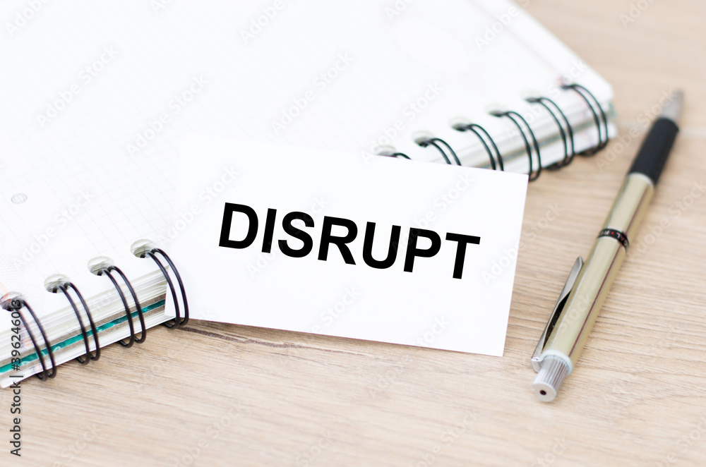 Aufkleber business card with disrupt text on the table, next to a notebook and a pen.