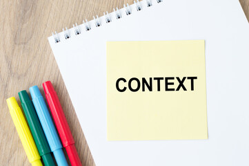 the inscription on the yellow sheet for notes text CONTEXT which is attached to the notebook on the table.