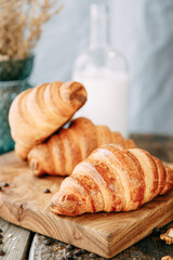 Freshly baked croissants on a wooden table. Breakfast with croissants and milk close-up.