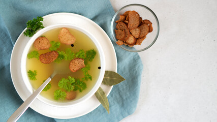 Homemade chicken bone broth in white bowl with bay leaves, parsley and peppercorns. Health benefits. Collagen is good for joints.