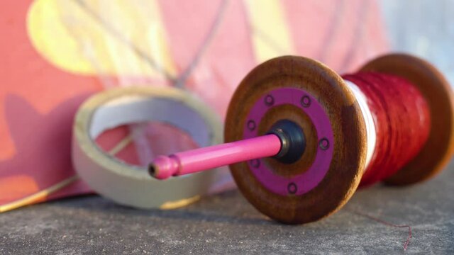 pull back shot showing the essential handmade paper and wood kite,paper tape and charkhi spool of saddi plain and manjha glass covered thread for kite fighting during the indian festival of Makar