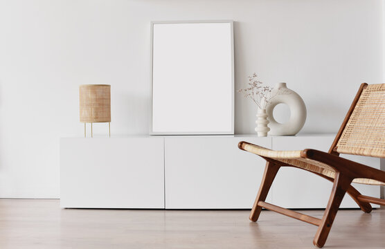 Blank picture frame mockup on white wall. White living room design. View of modern scandinavian style interior with chair. Home staging and minimalism concept