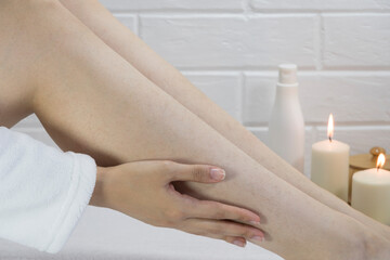 Obraz na płótnie Canvas Hair on the legs of women. Skin care, body. Preparing legs for the procedure of hair removal. Body positive, self-acceptance, feminism. Apply the cream, massage. Strawberry legs, keratosis. Relaxation