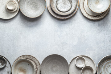 handmade ceramics, empty craft ceramic plates and bowls on light background, top view, border - obrazy, fototapety, plakaty