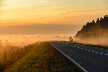 In the foreground the road passing through the field is covered with a thin layer of fog