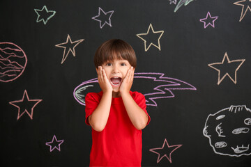 Cute little boy near black wall with drawn space