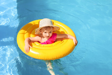 Cute baby girl with inflatable ring in swimming pool