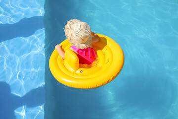 Cute baby girl with inflatable ring in swimming pool