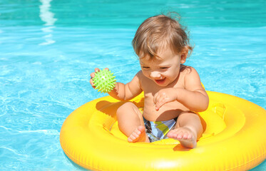 Cute baby boy with inflatable ring in swimming pool