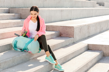 Sporty young woman with bag outdoors