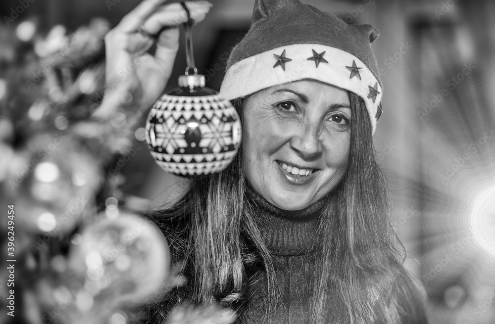 Sticker Happy Brunette Woman decorating Christmas Tree at home, holding Red Christmas Ball