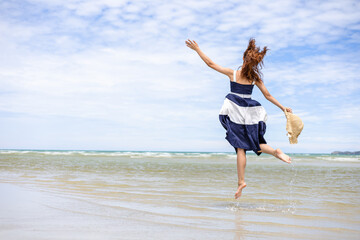 Woman barefoot jump in the water on summer along wave of sea water and sand on the beach.