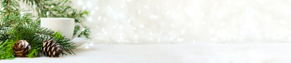 a tree branch, two coffee cups and cones on a white background with garlands. The concept of Christmas