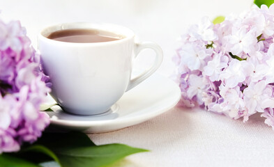 Obraz na płótnie Canvas white coffee Cup with branch of lilac on white background. The concept of tenderness and celebration of Valentine's day