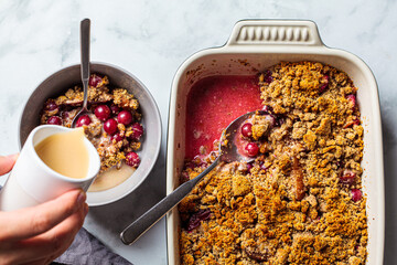 Healthy vegan dessert concept. Berry crumble with oat milk for breakfast, top view, white marble background.