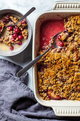 Healthy vegan dessert concept. Berry crumble with oat milk for breakfast, top view, white marble background.