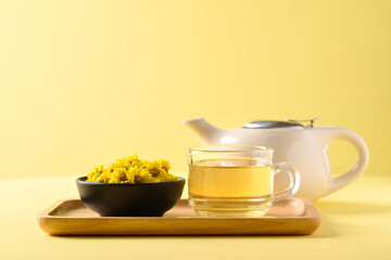 Organic Chrysanthemum flower tea in a cup and teapot on yellow background, Healthy Herbal drink