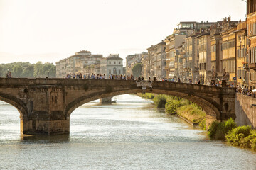 Fototapeta na wymiar Tourists gather on the Holy Trinity Bridge(Ponte Sanata Trinita) that crosses the Arno river in the late afternoon