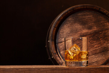 Scotch whiskey glass and old wooden barrel