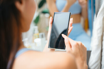 Healthy woman using smartphone buying vegan food at home.