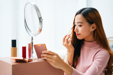 Beautiful asian woman doing makeup at home.