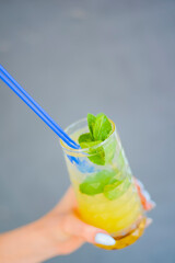 Young beautiful woman holding cocktail in hand. Fruit juice, delicious citrus cocktail. Cold drink, alcohol beverage.
