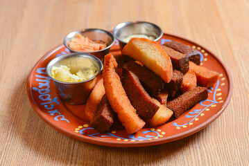 Crouton stack in a porcelain plate with different kinds of sauce. Delicious snack for beer.