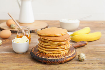 Board with tasty banana pancakes on table