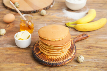 Board with tasty banana pancakes on table