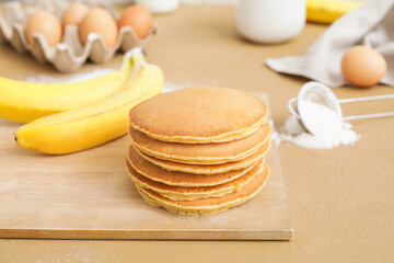 Board with tasty banana pancakes on table