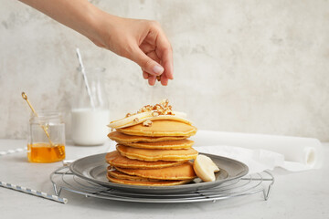Woman decorating tasty banana pancakes on plate