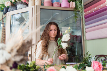 Young woman florist makes a bouquet at workplace, small business concept, lifestyle