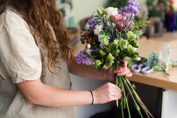 Young woman florist work with flowers at workplace, small business concept, lifestyle, cropped portrait, flowers close up