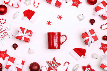 Red coffee mug with Christmas gifts and decorations on white background. Top view, flat lay.