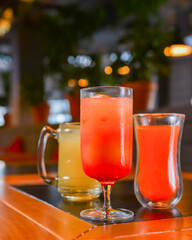 Three cocktails drinks on wooden table at bar indoors. Delicious fruit drinks for refreshment. Alcohol beverage.