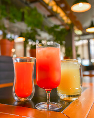 Three cocktails drinks on wooden table at bar indoors. Delicious fruit drinks for refreshment. Alcohol beverage.