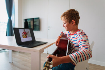 kid having guitar lesson online, teenage boy on remote music lesson