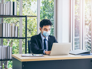 Young handsome Asian businessman in suit in office.