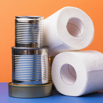 Various cans of canned food and rolls of toilet paper on the table. Concept on the topic of food poisoning