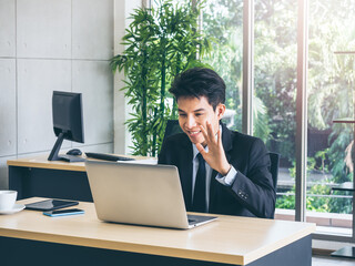 Young handsome Asian businessman in suit in office.