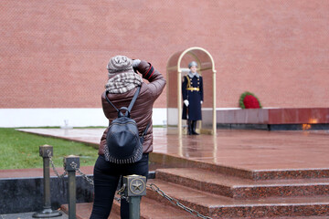 Girl tourist taking pictures of the honor guard near the Kremlin wall in Moscow. Russian military,...