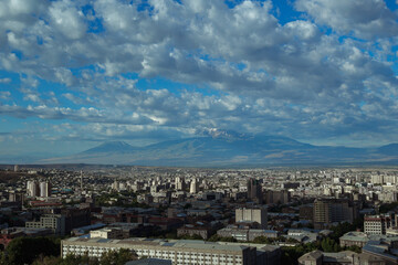 Fototapeta na wymiar Scenery of city of Yerevan with rooftops of residential buildings on sunny day on background of mountain range in Armenia 