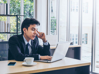 Fototapeta na wymiar Young handsome Asian businessman in suit in office.