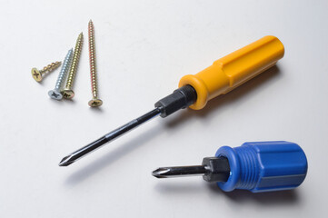 two different screwdrivers and several screws on a white background. close-up.